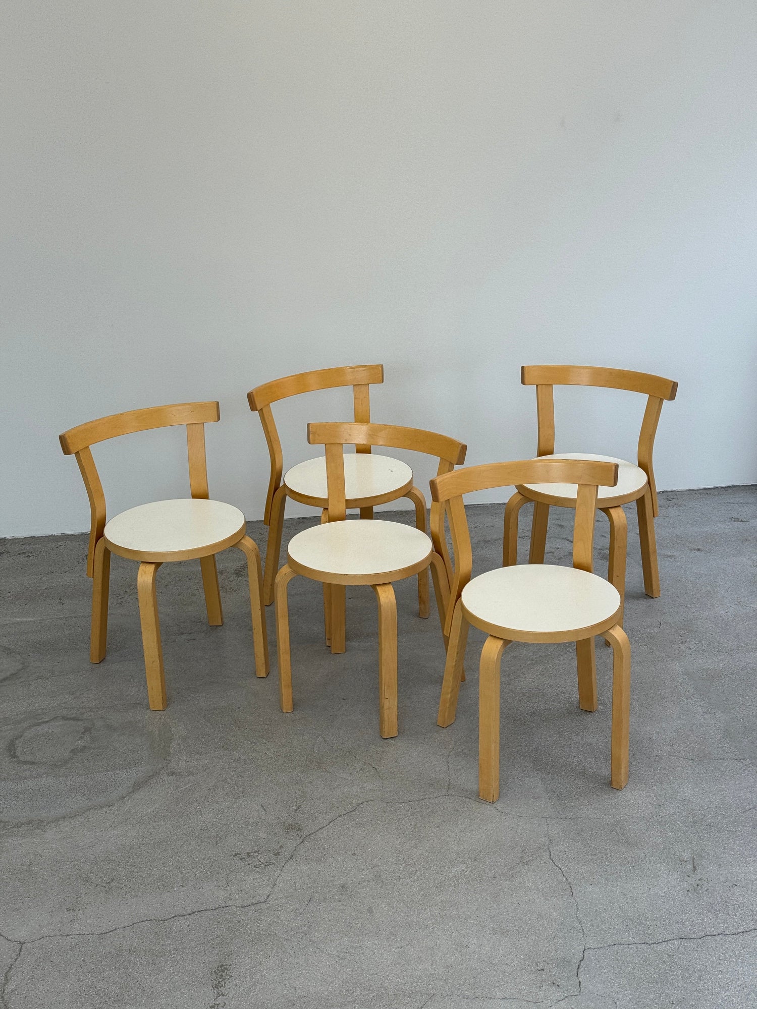 Wooden artek 69 chairs stacked against a gray wall