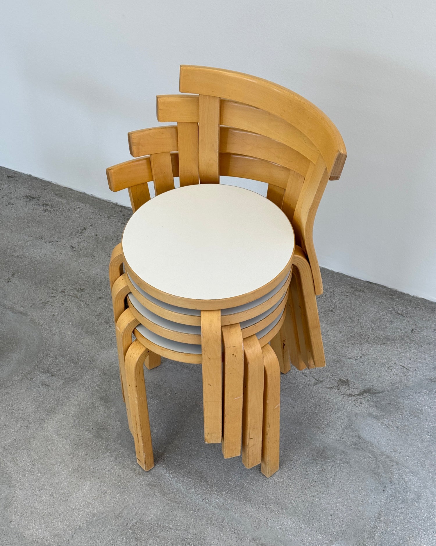 Wooden artek chairs stacked on a gray surface