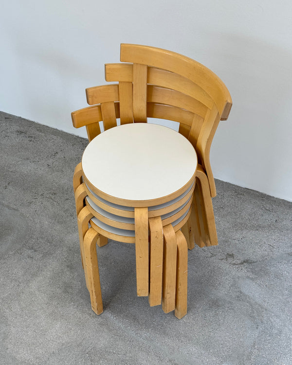 Wooden artek chairs stacked on a gray surface
