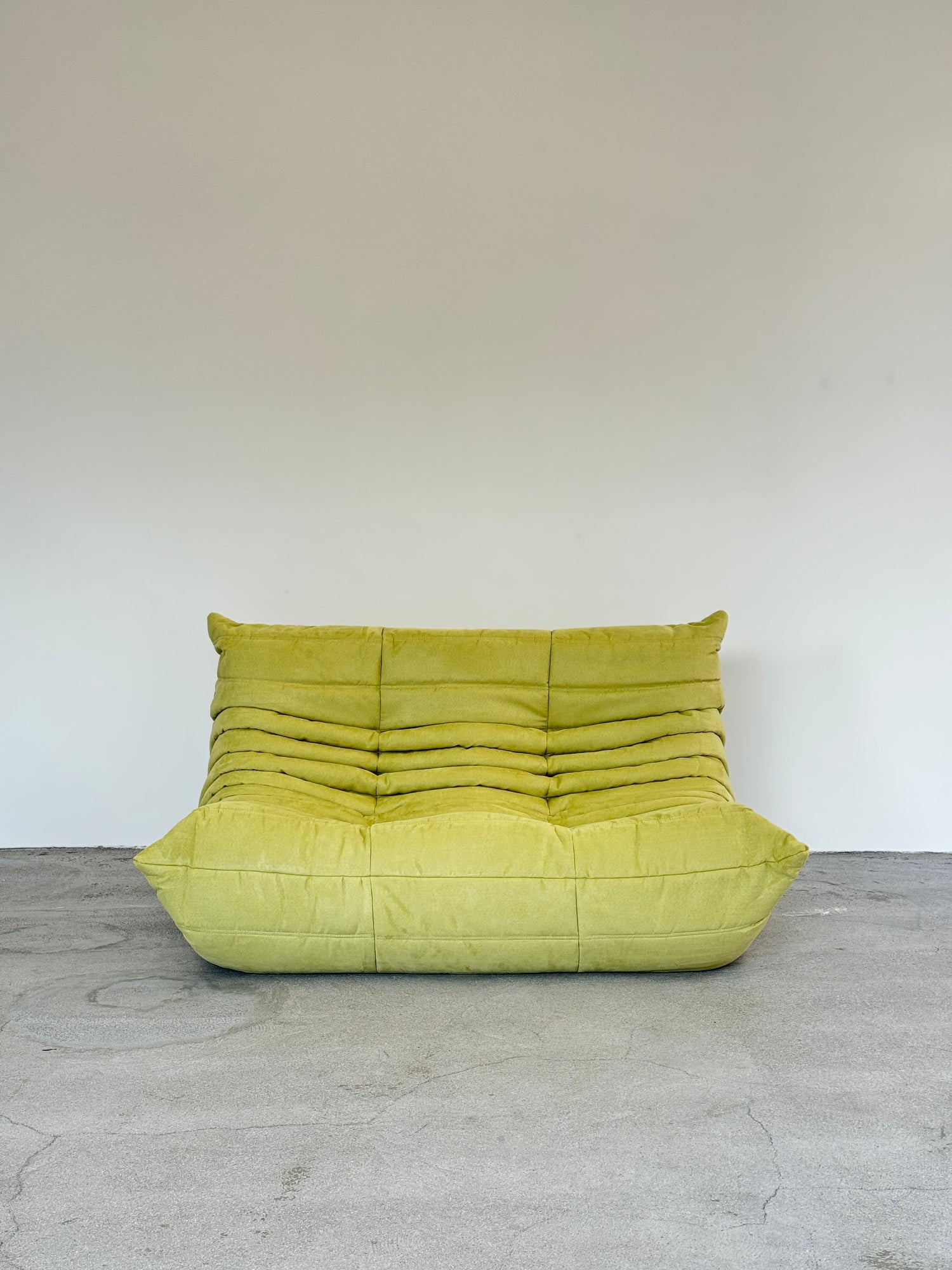 Green ligne roset togo on a white and gray concrete wall