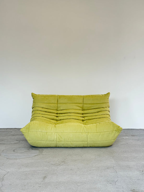 Green ligne roset togo on a white and gray concrete wall