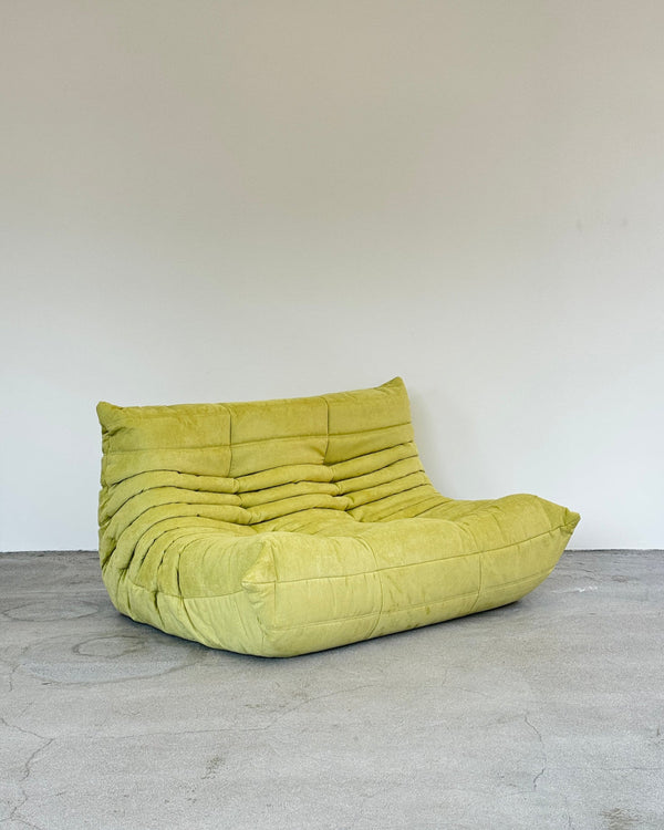 Green Togo sofa on a light gray floor with a white wall background
