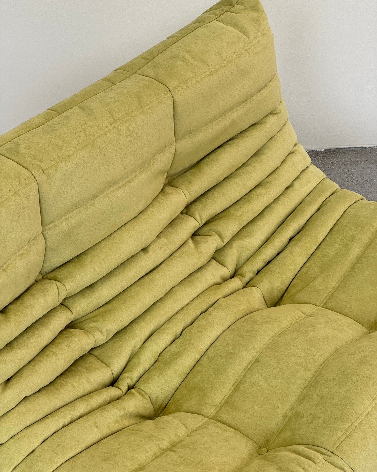 Close-up of a green Togo sofa on a white background