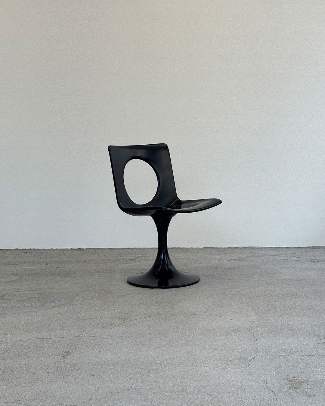 Black chair on a gray floor with a white wall background