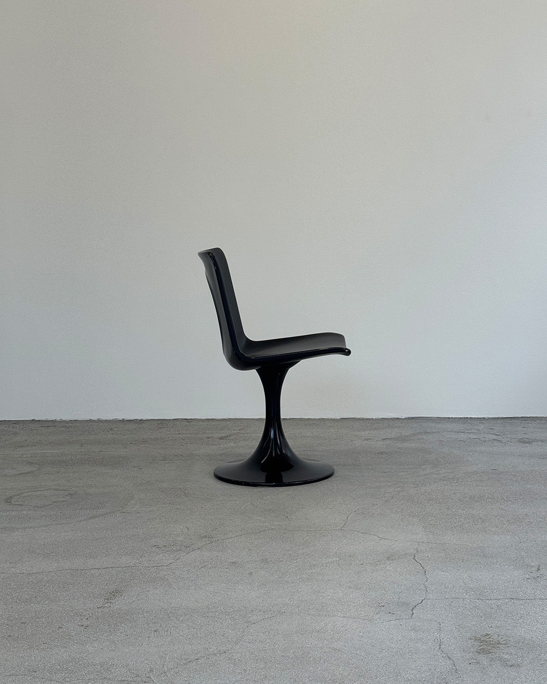 Black chair on a gray floor with a white wall background