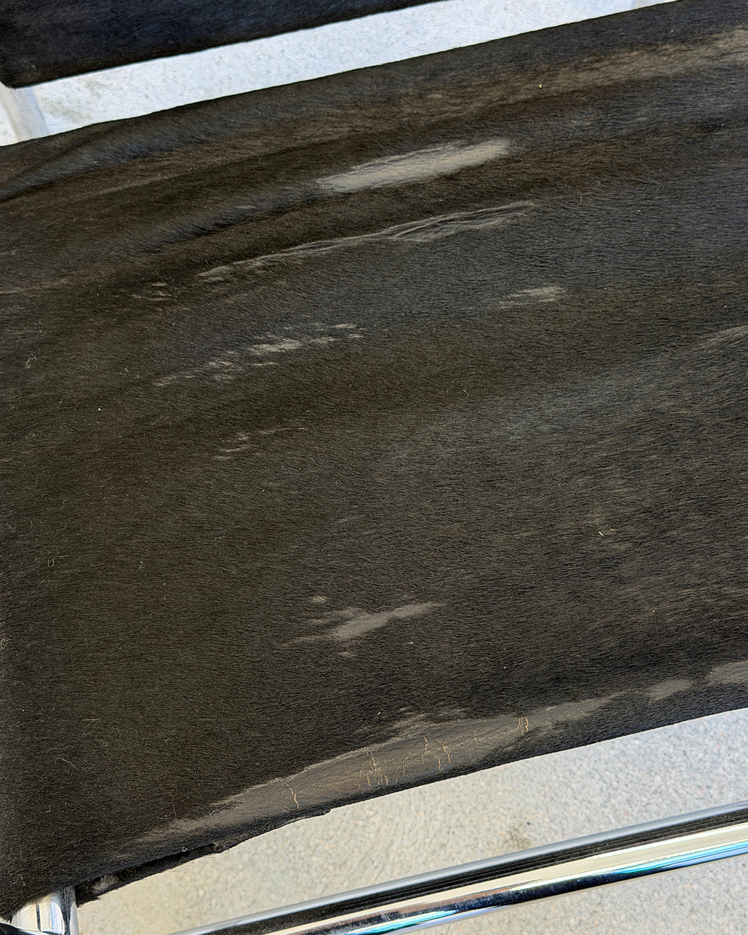 Close-up of a dark brown leather surface with visible wear and tear.