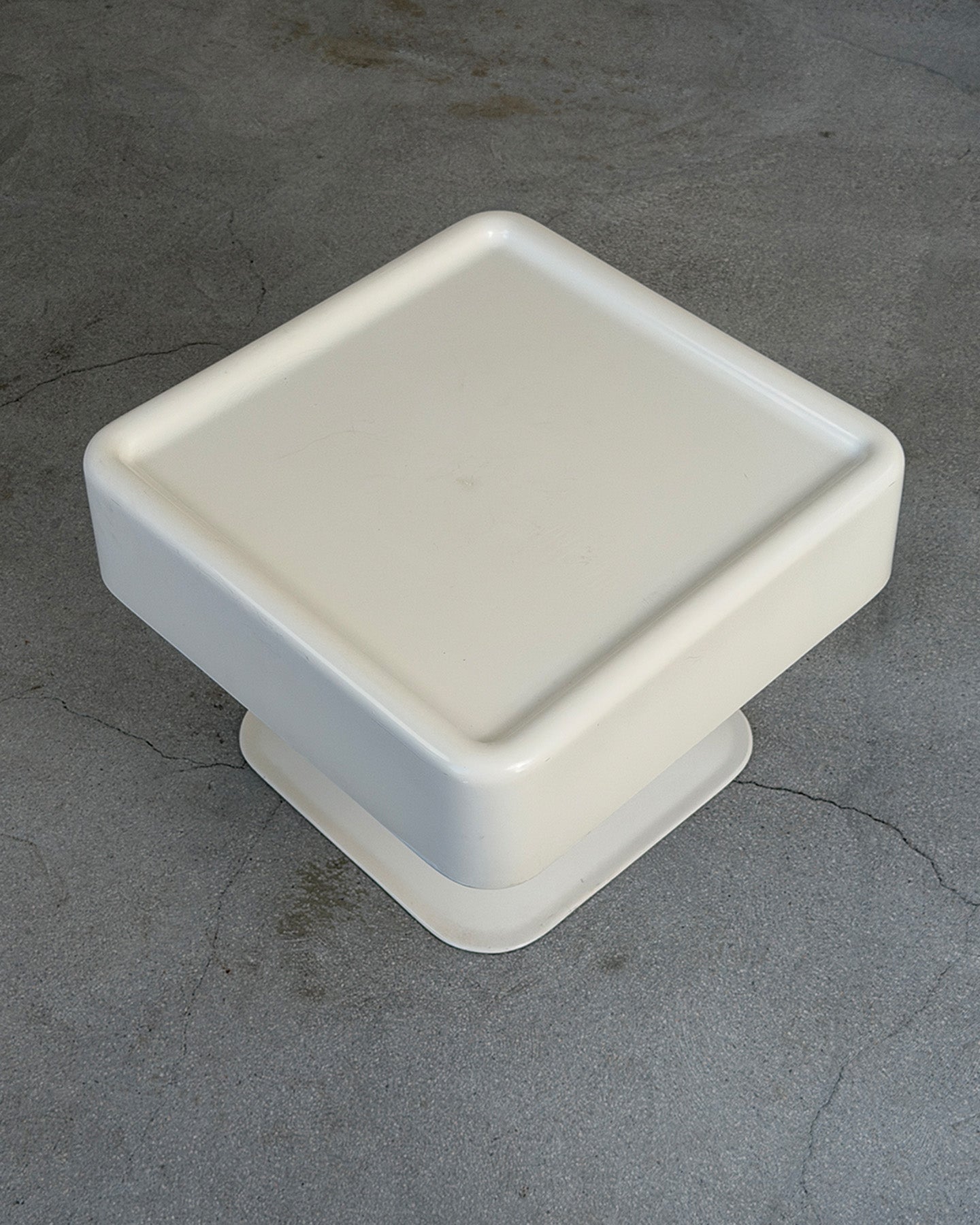 White square plastic object on a gray concrete surface