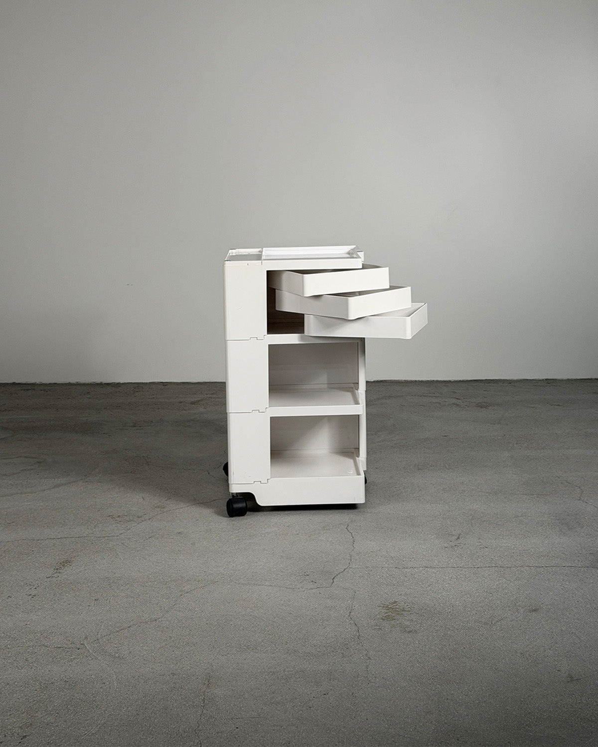 White rolling cart with drawers on a gray floor and background