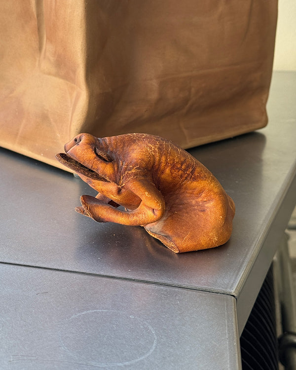 Brown leather Deru frog figure on a gray surface