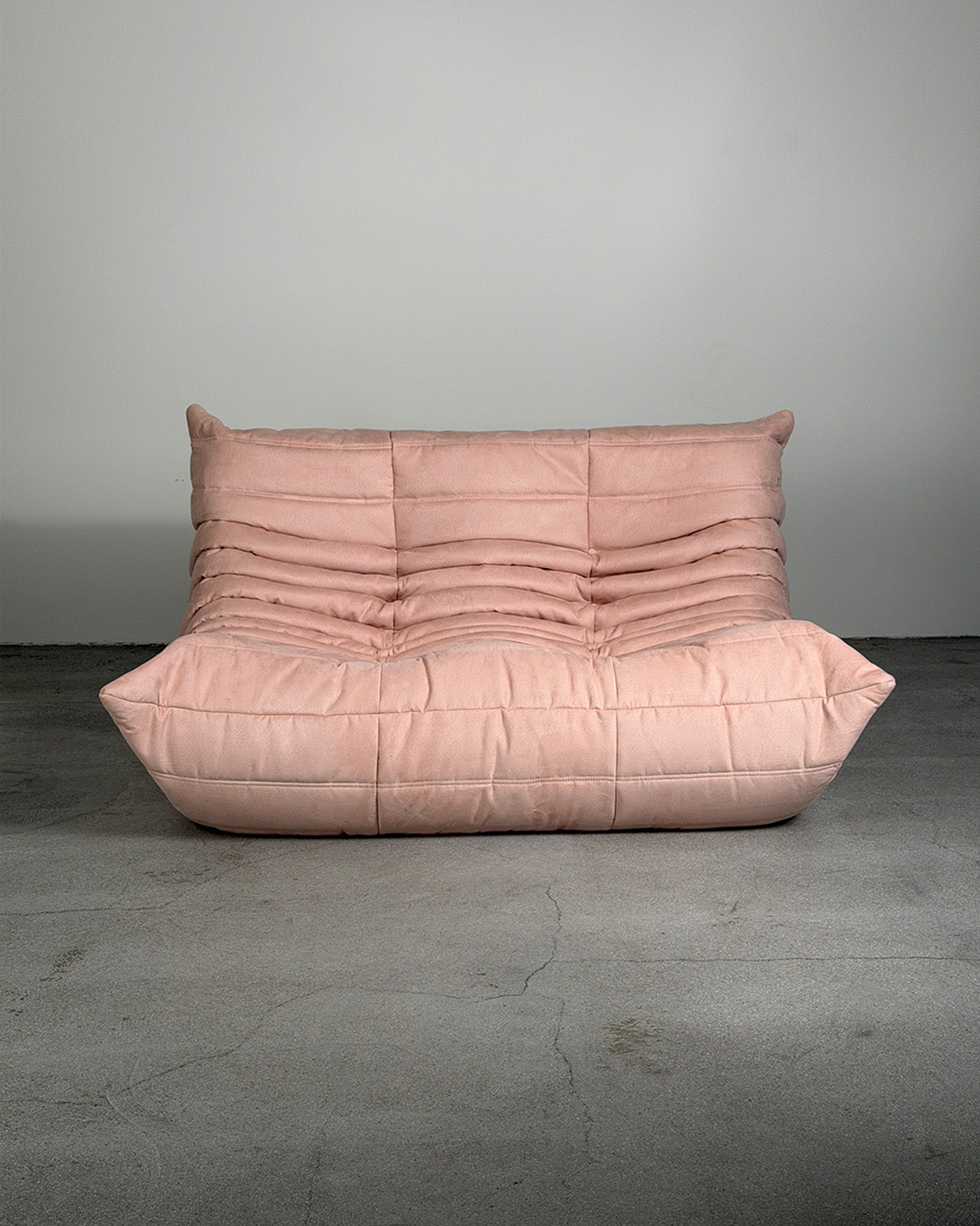 Pink togo sofa against a gray wall on a gray floor