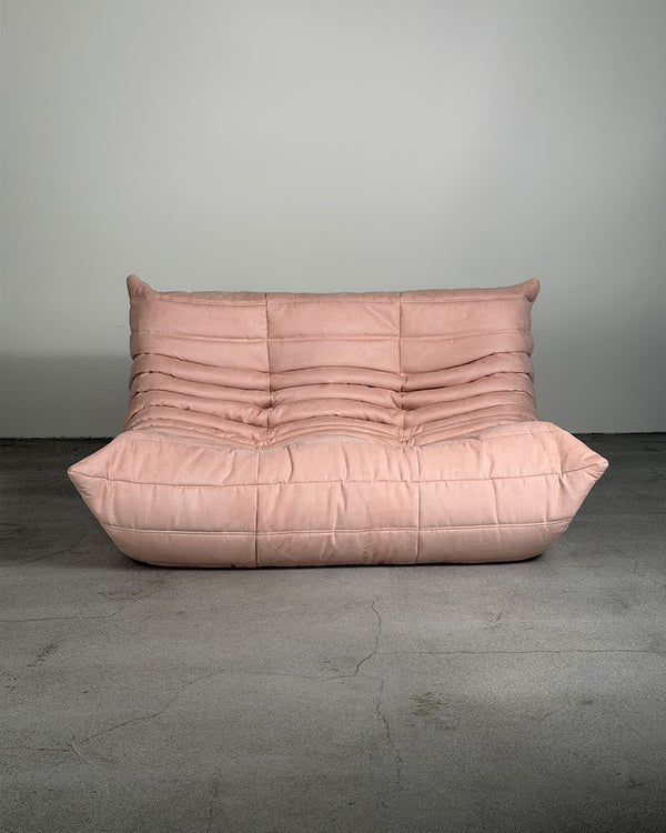 Pink togo sofa against a gray wall on a gray floor