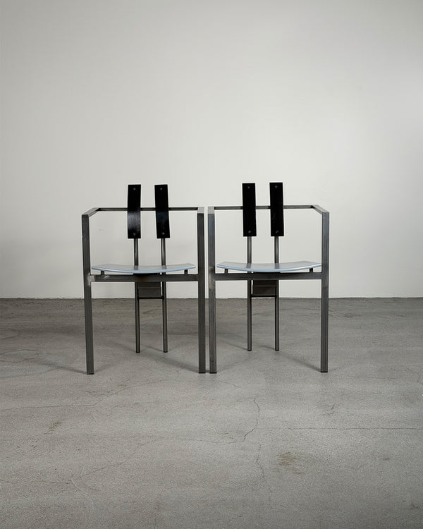 Two black chairs with glass seats on a gray floor and white wall background