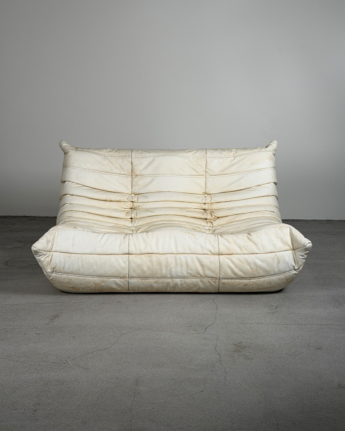 White sofa with a textured surface on a gray floor and background