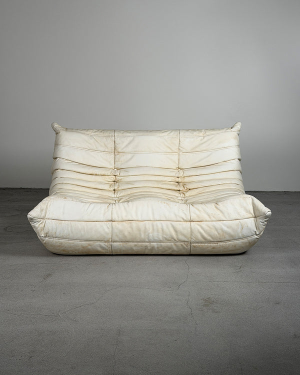 White sofa with a textured surface on a gray floor and background