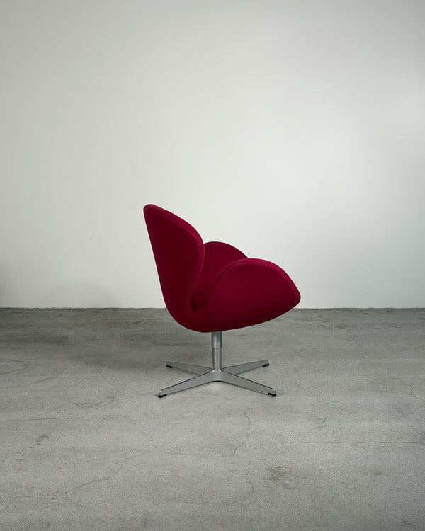 Red swivel chair on a gray floor with a white wall background