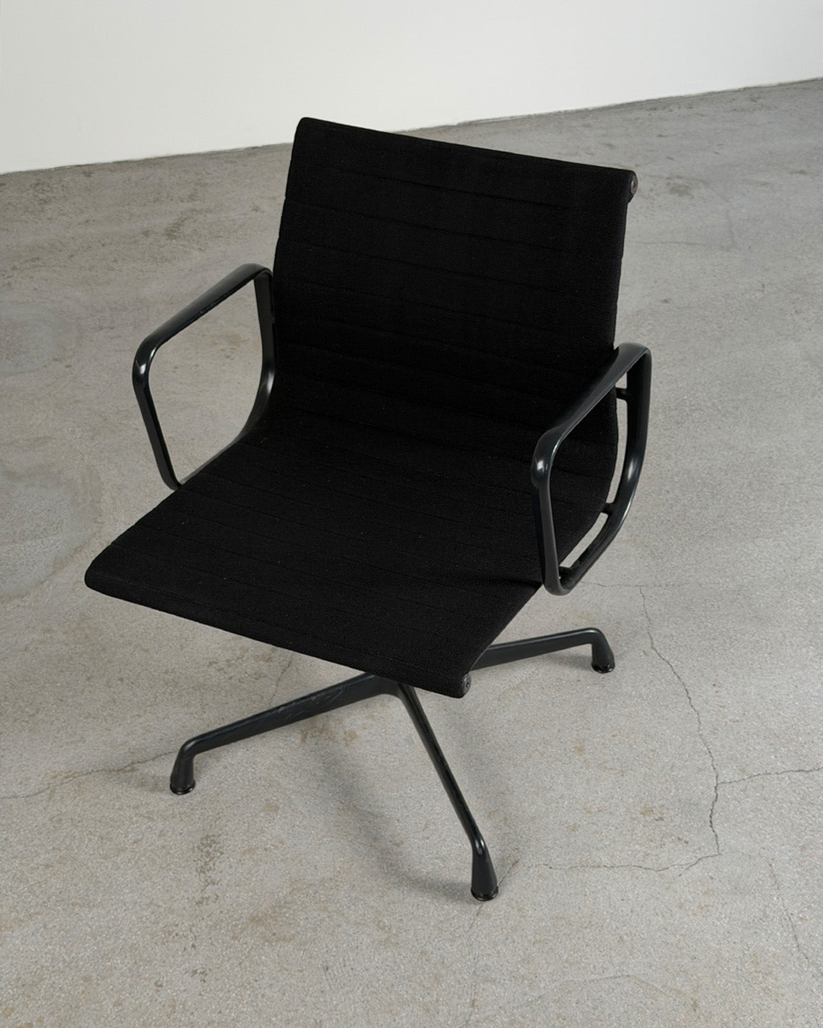 Black office chair with metal frame on a concrete floor