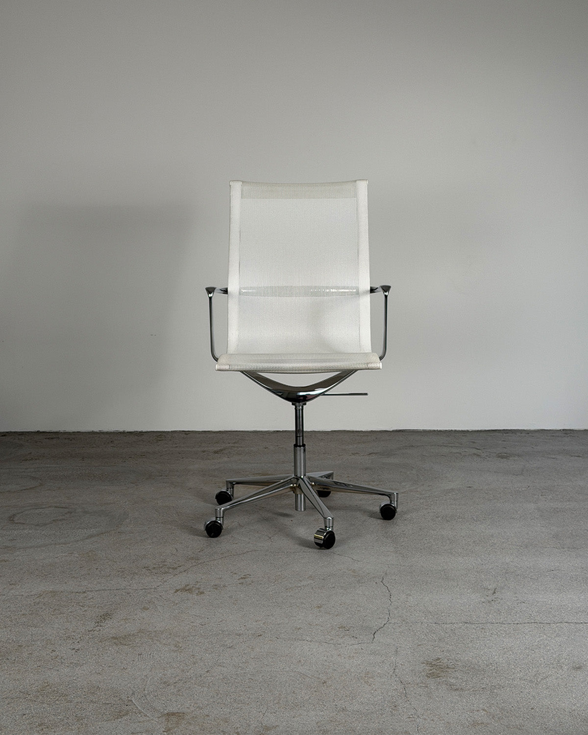White office chair with mesh backrest on a gray floor and white wall