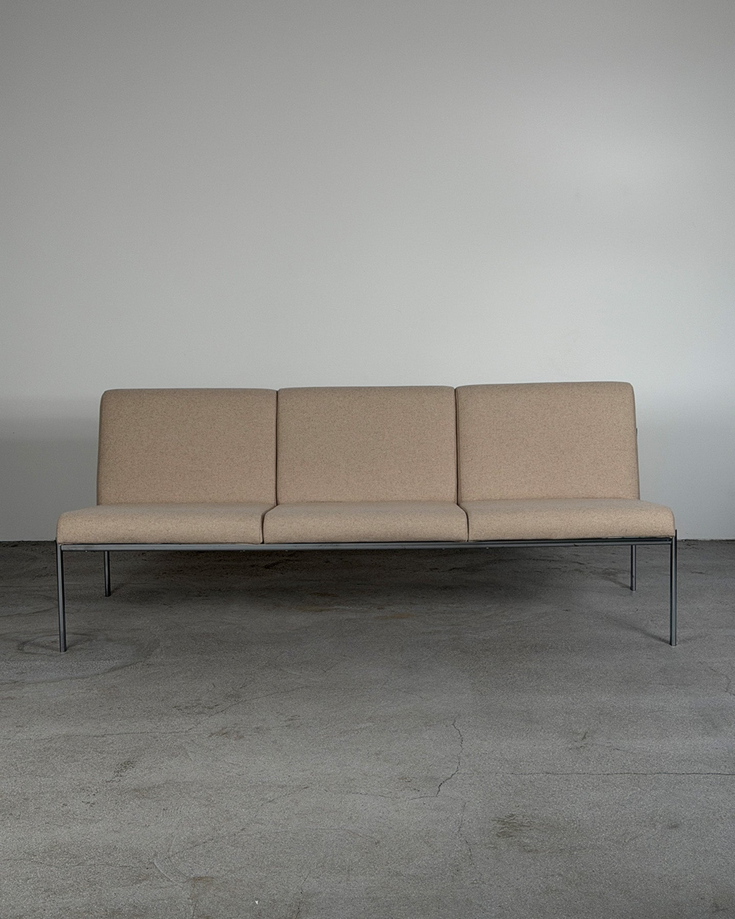 Beige sofa with metal legs on a gray floor and background