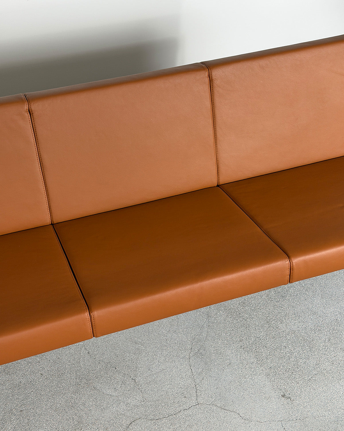 Brown leather bench against a white wall