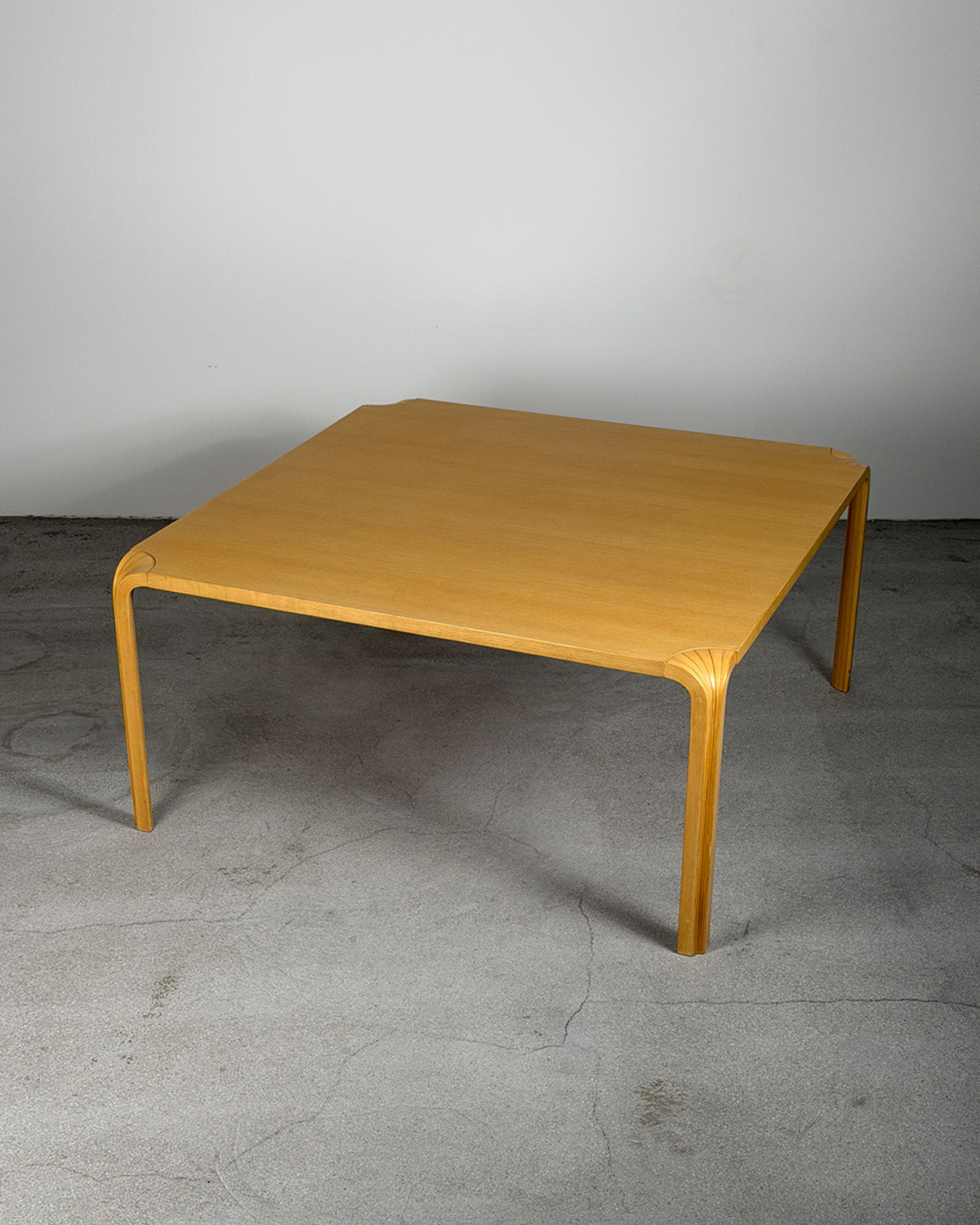 Wooden table on a gray floor with a plain white wall background