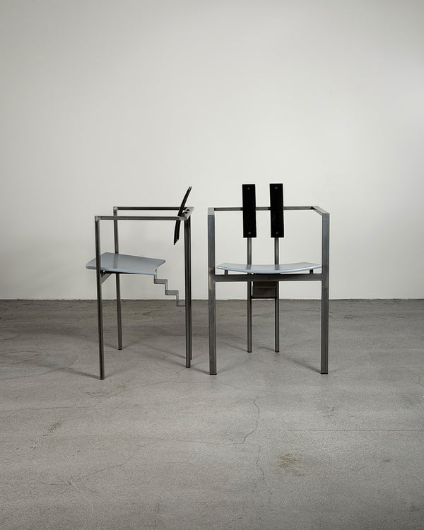 Two modern chairs with glass seats on a concrete floor against a white wall.
