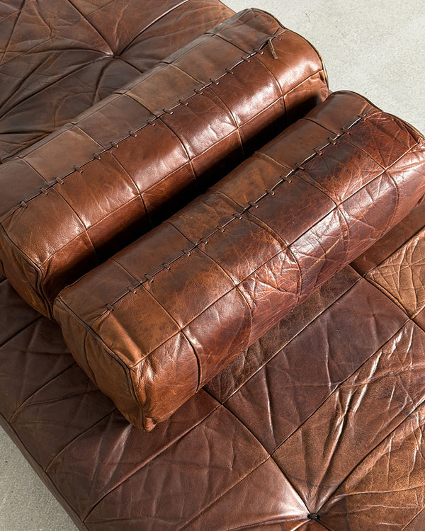 Brown leather sofa with a quilted pattern on a light gray background