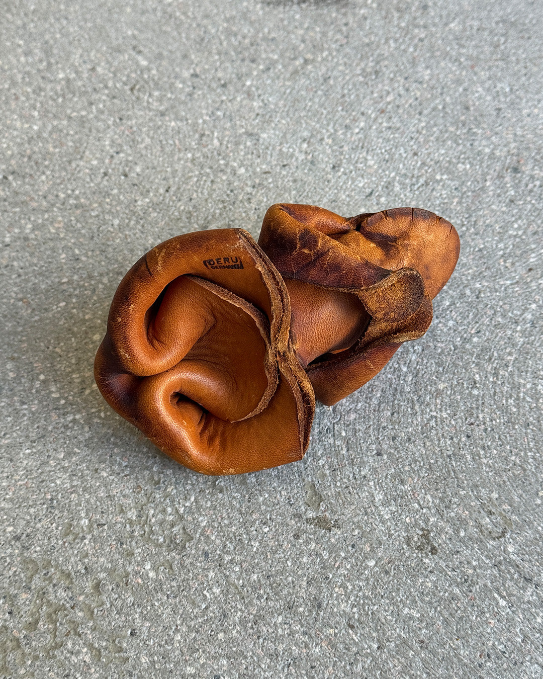 Brown leather Deru frog figure on a gray surface