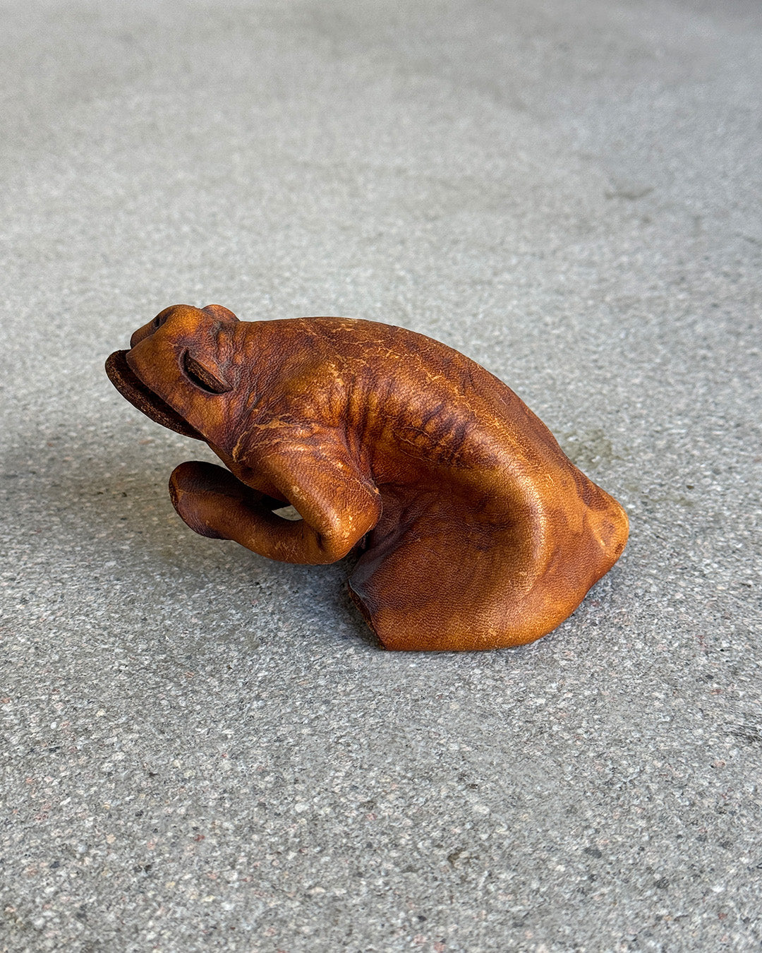 Brown leather frog figure on a gray surface