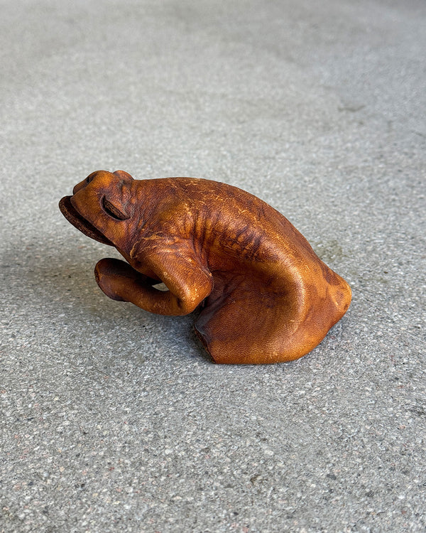 Brown leather frog figure on a gray surface