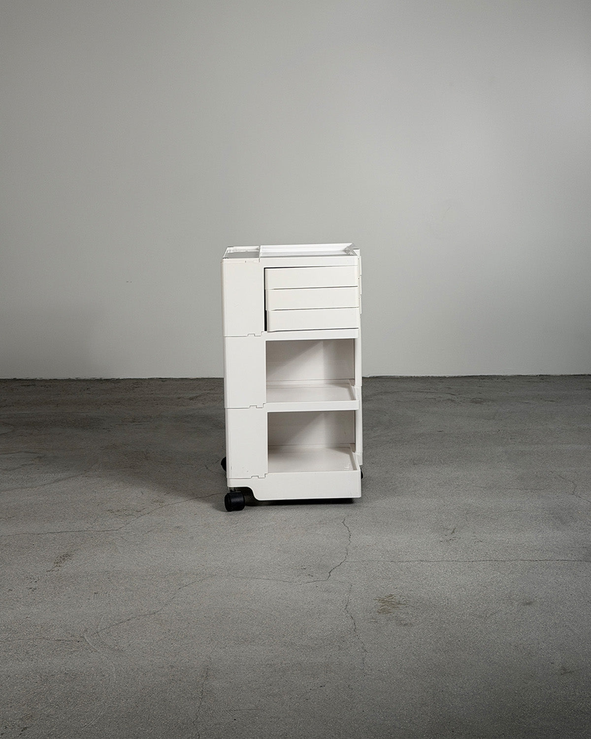 White rolling cart with multiple drawers on a gray floor and background