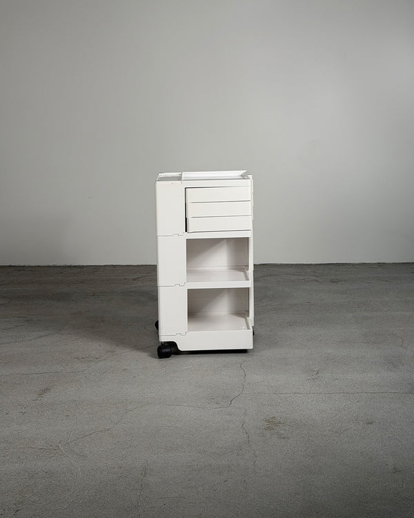 White rolling cart with multiple drawers on a gray floor and background