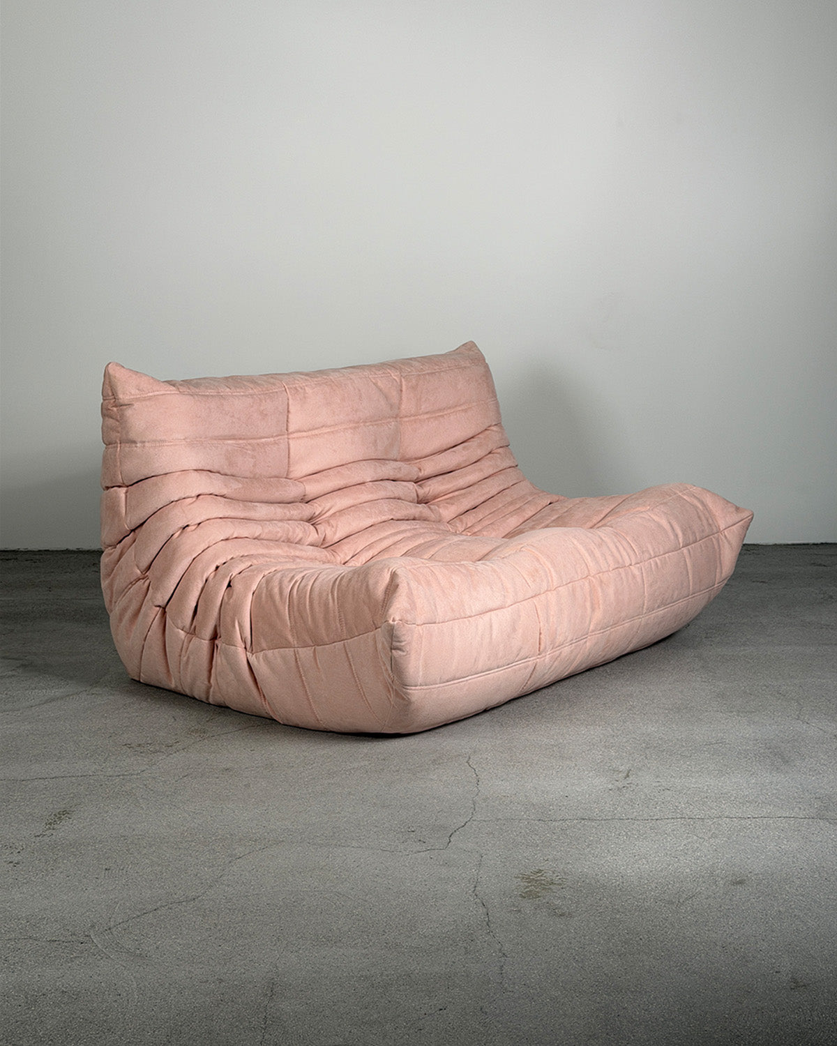 Pink togo chair on a gray floor with a gray wall background