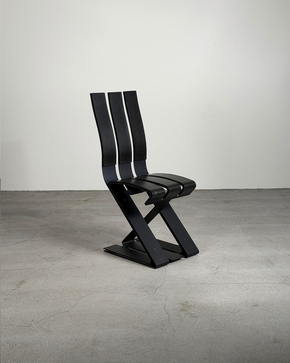 Modern ron arad school chair in black on a gray floor with a white background