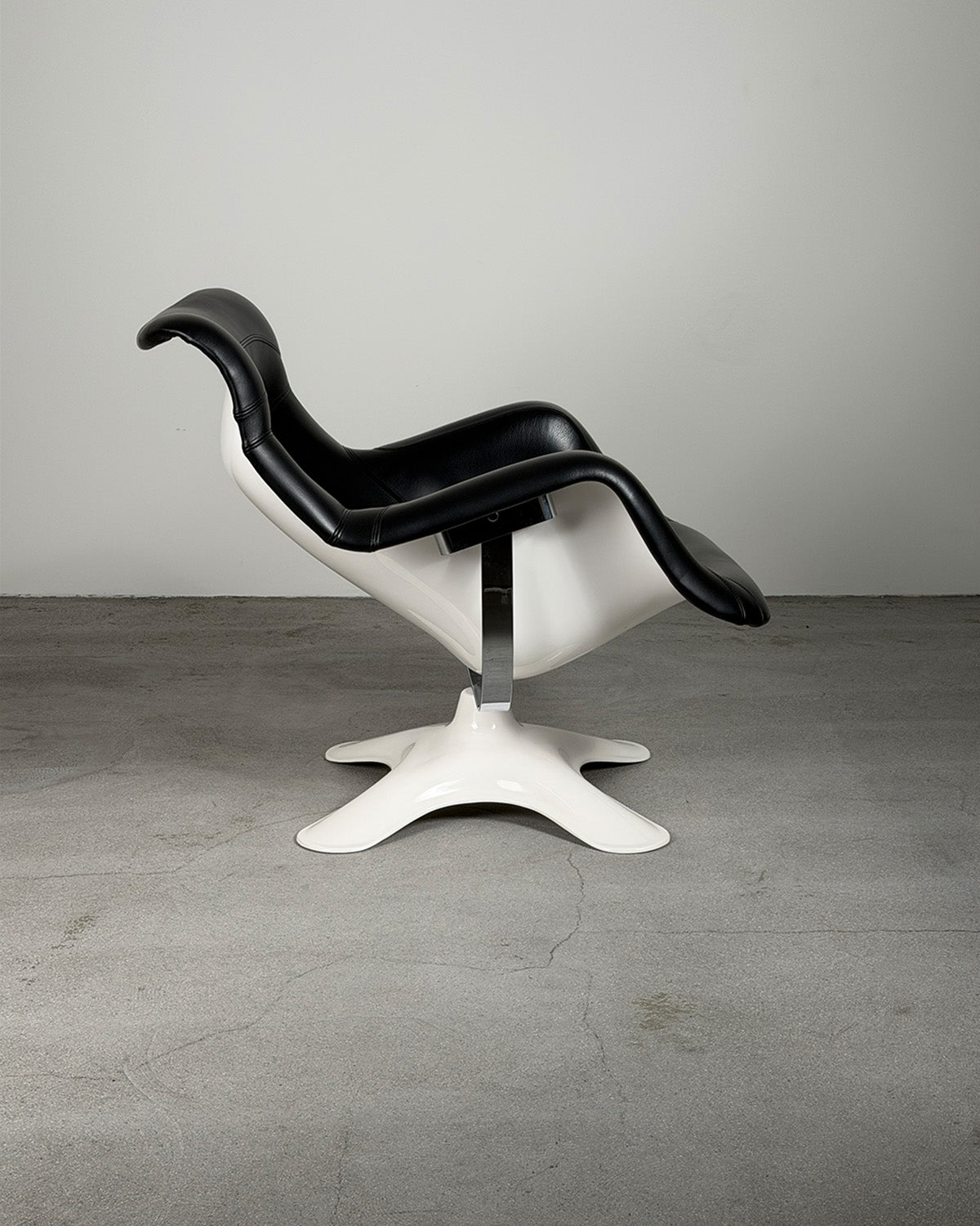 Modern chair with black seat and white base on a gray floor and background