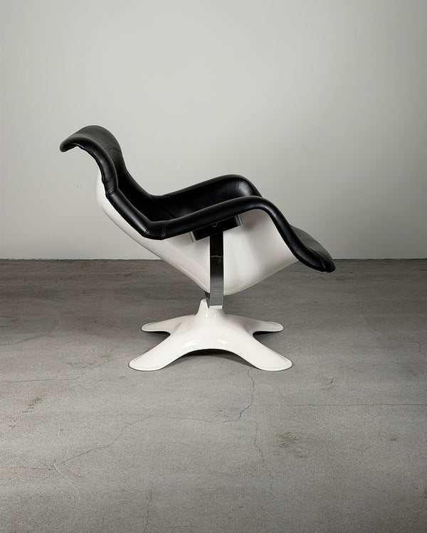 Modern chair with black seat and white base on a gray floor and background