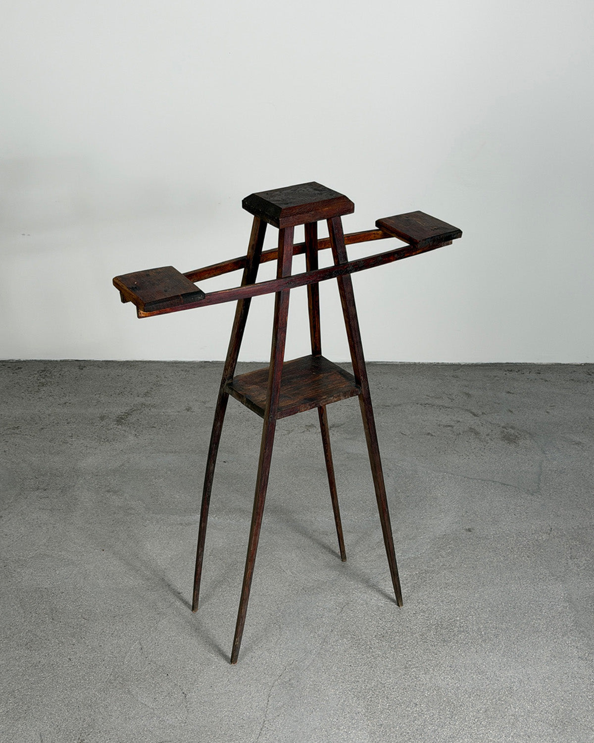 Wooden stand with multiple shelves on a gray floor and white wall background