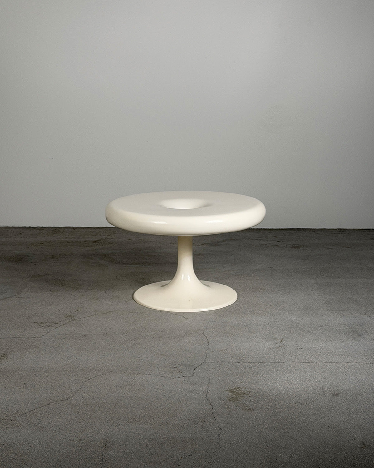 White Eero Aarnio Kanttarelli table on a gray surface with a white background