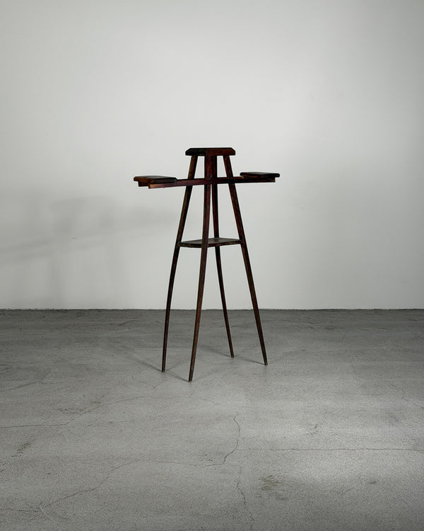 Wooden bar stool against a plain wall on a gray floor