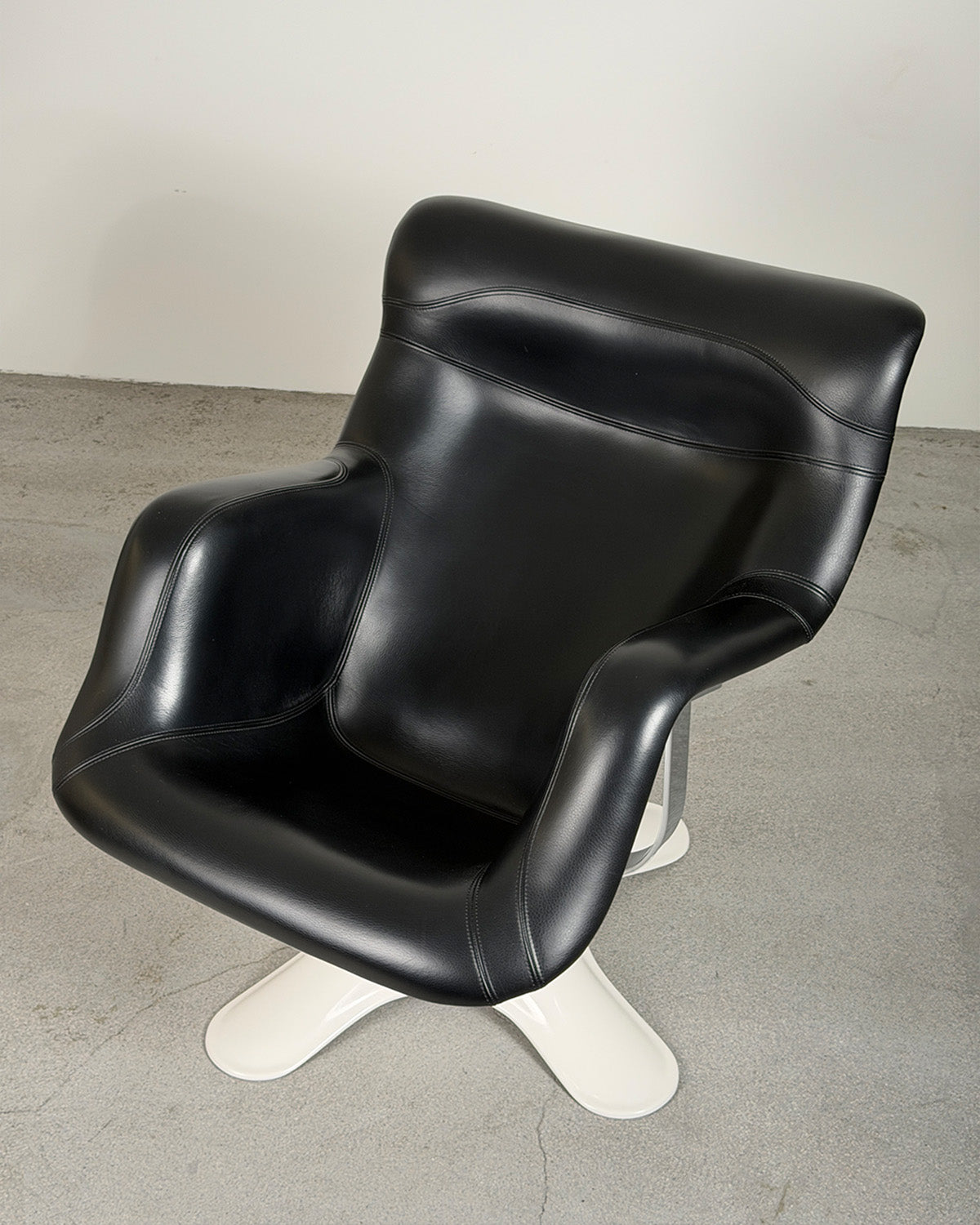 Black leather chair with white base on a gray floor