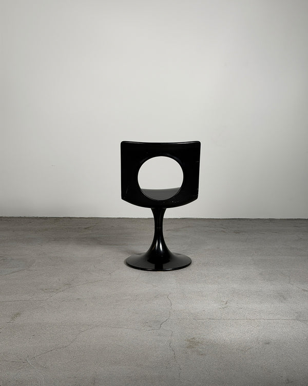Modern black chair on a gray floor with a white wall background