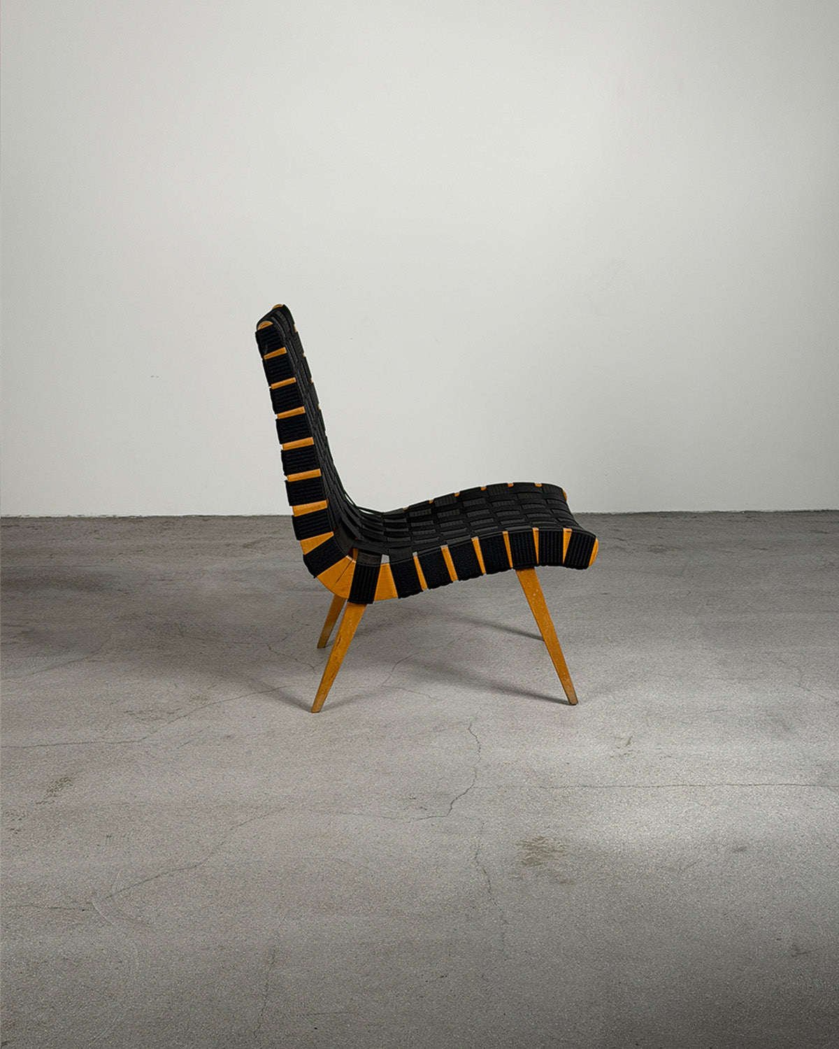 Modern chair with black and yellow striped backrest on a gray floor and background